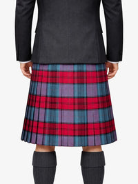 Person wearing a black jacket and red, blue, and purple plaid kilt on a white background